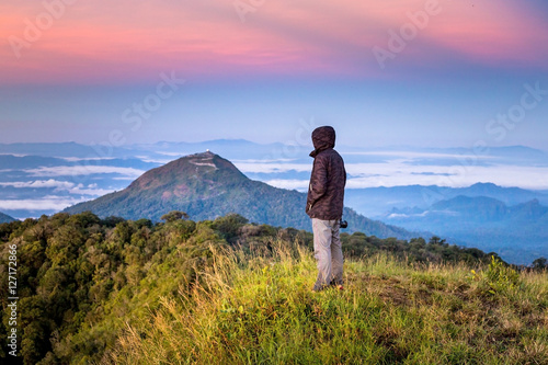 Man in hood standing on top of mountain with beautiful sun rise © golfnmd50