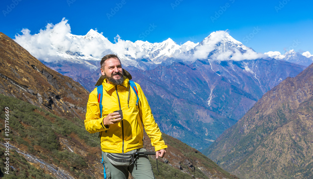 Happy Hiker in yellow Jacket drinking Tea in Mountains