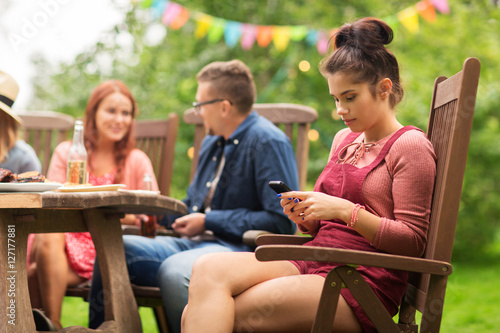 woman with smartphone and friends at summer party