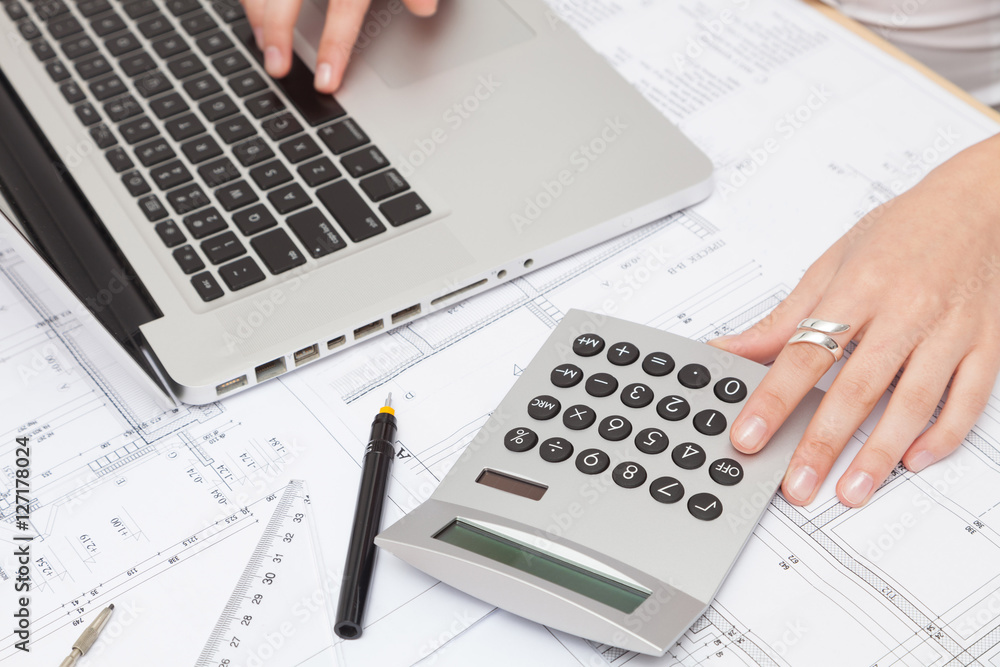 Architect analyzing investment charts with calculator Architect analyzing investment charts with calculator