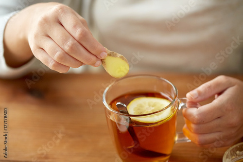 close up of woman adding ginger to tea with lemon