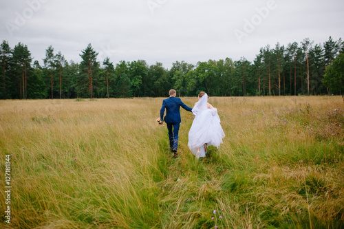 The bride and groom running across the field