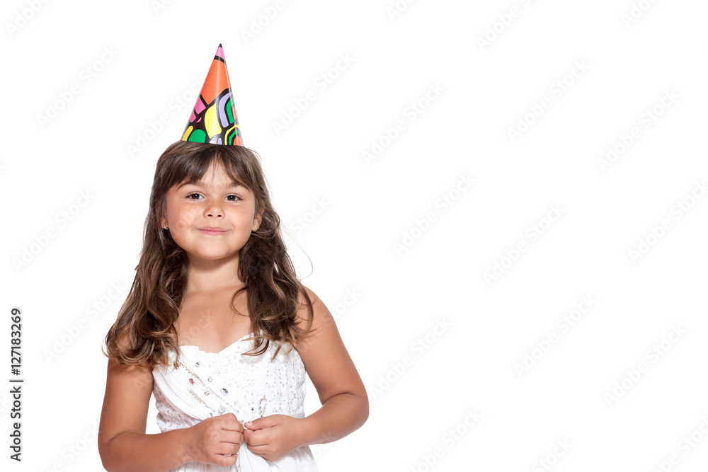 Cute little girl in white dress with paper hat on her head is standing facing the camera isolated on the white background. Free place for your text is in the right side of the photo. Cute little girl in white dress with paper hat on her head is standing facing the camera isolated on the white background. Free place for your text is in the right side of the photo.