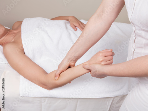 Therapist doing therapeutic deep tissue massage on  muscles of a woman's  forearm