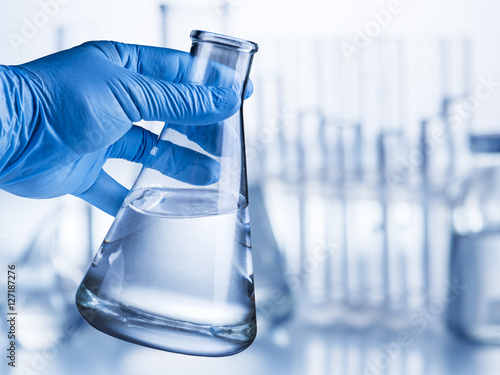 Cuadro en lienzo Laboratory beaker in analyst's hand in plastic glove.