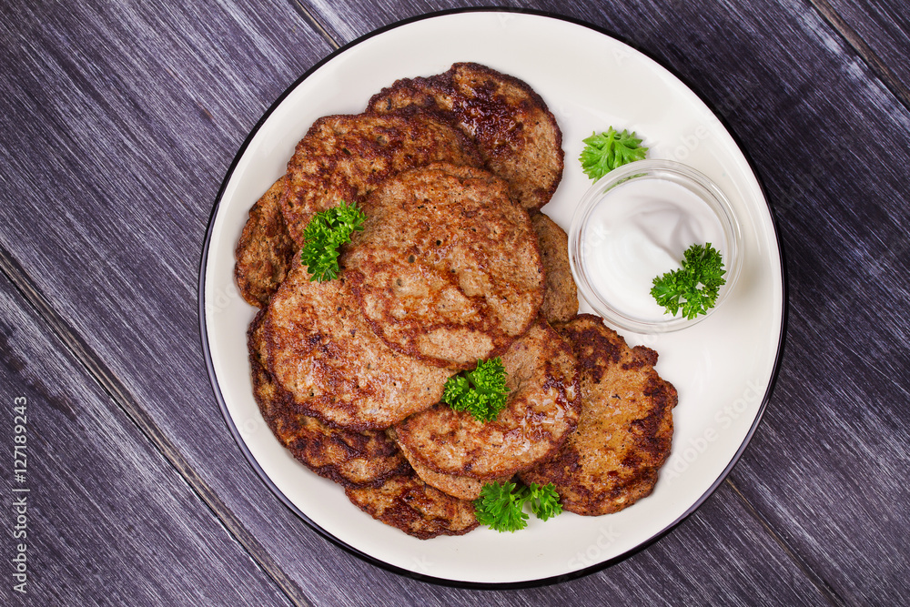 Liver Patties with Sour Cream and Parsley. Liver Cakes or Fritters of Liver. Healthy snack or take-away lunch bites. View from above, top studio shot Liver Patties with Sour Cream and Parsley. Liver Cakes or Fritters of Liver. Healthy snack or take-away lunch bites. View from above, top studio shot