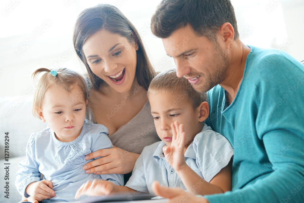 Family sitting on sofa reading book with kids Family sitting on sofa reading book with kids