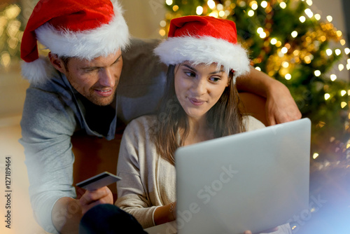 Couple buying Christmas gifts online with laptop