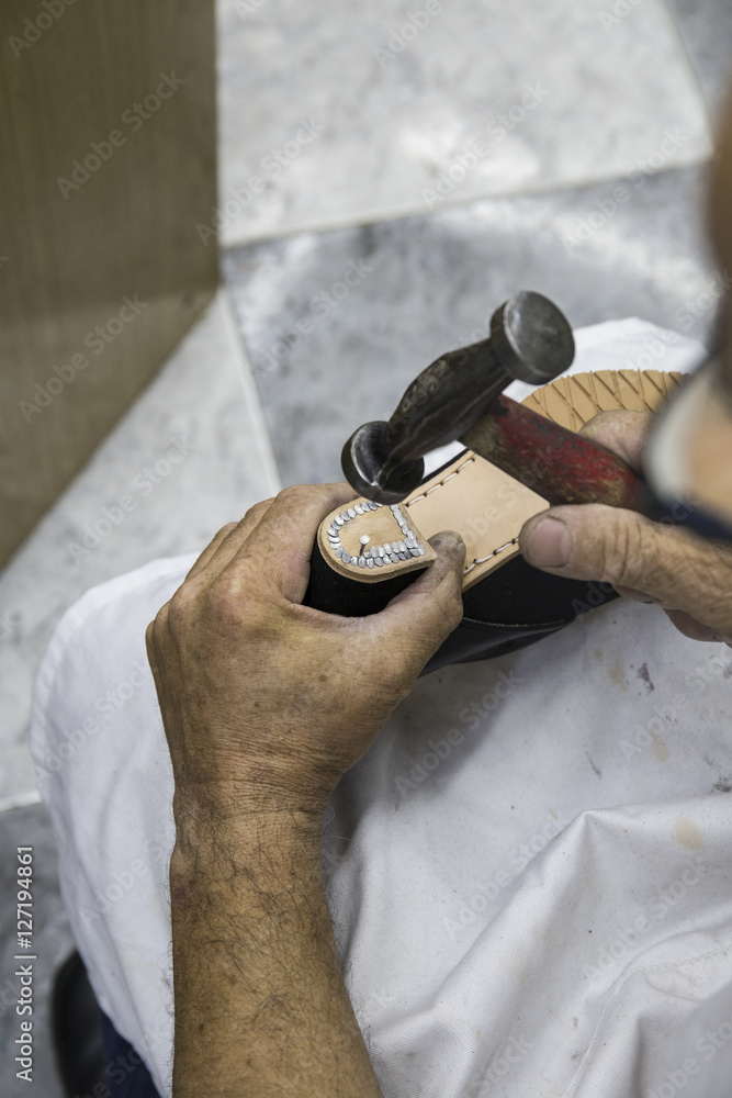 Shoemaker nailing nails in the heel of a shoe foto de Stock | Adobe Stock