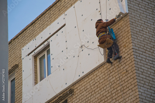 Rope access worker makes insulation with styrofoam photo