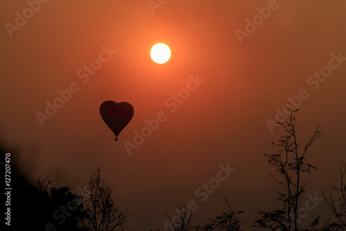 Silhouette of heat balloon over sunset background