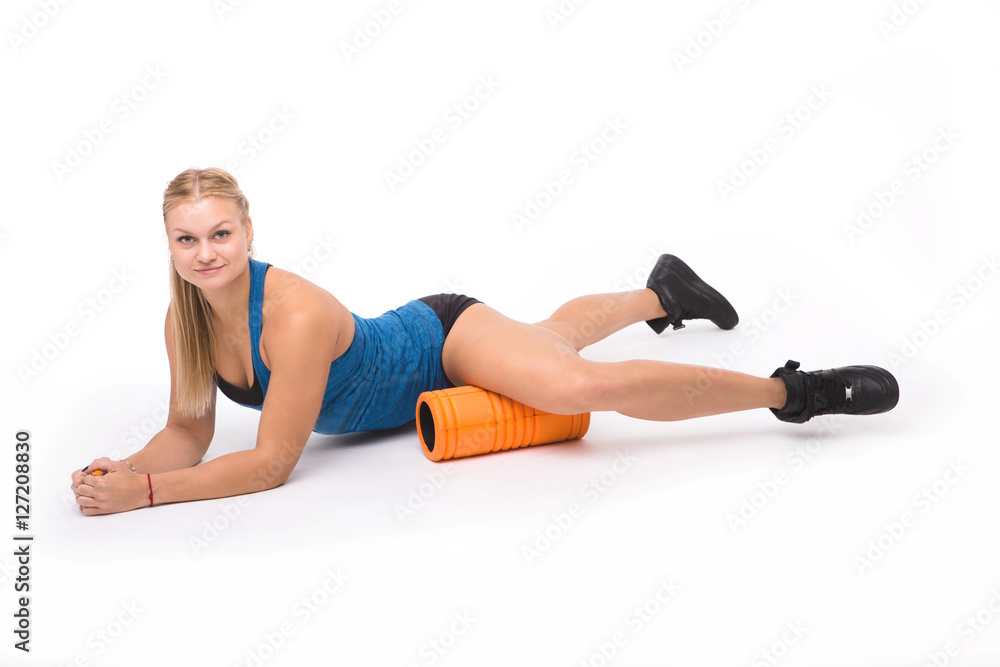 Happy lady lying on floor with massage device after training. Professional fitness woman training isolated on white background in studio.