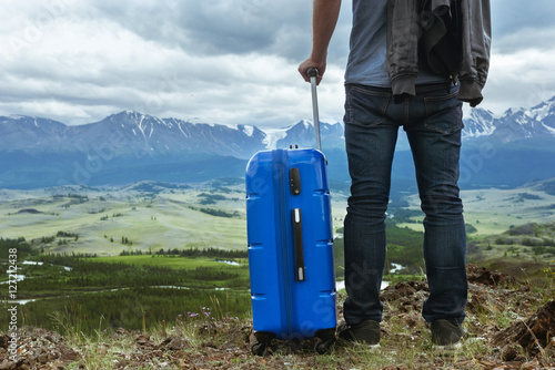 Man with suitcase mountains travel concept