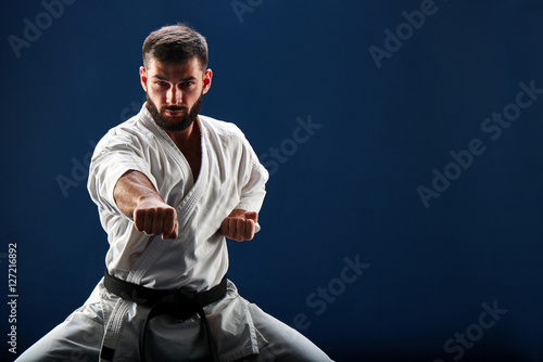 Karate man in a kimono in fighting stance on a blue background photo