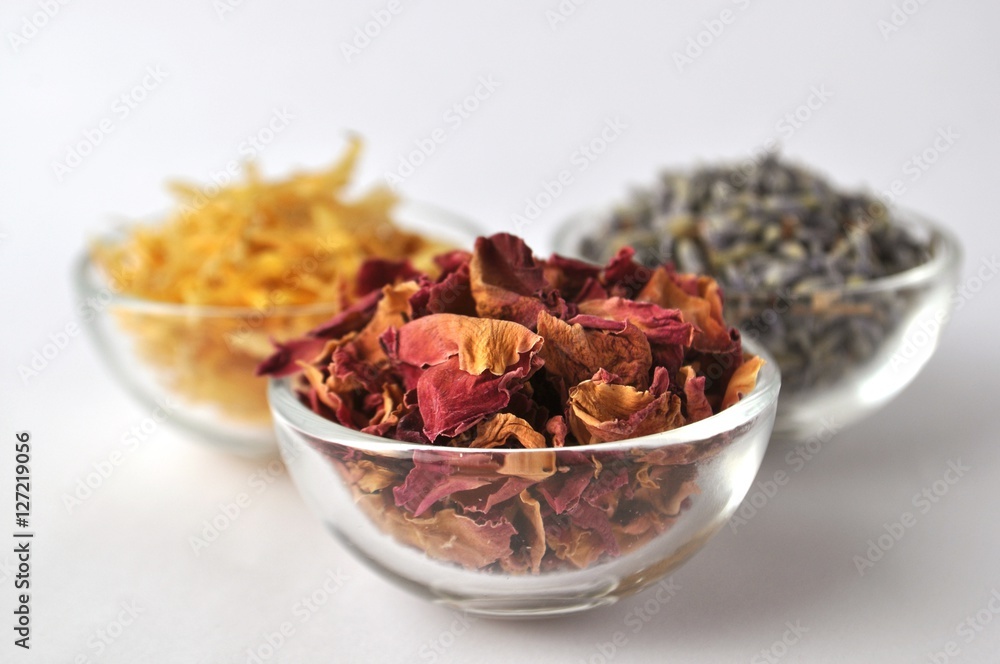 Dried flowers of marigold (calendula), lavender and rose for beauty treatments in clear glass bowls Dried flowers of marigold (calendula), lavender and rose for beauty treatments in clear glass bowls