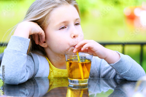 Adorable little girl drinking apple juice in cafe