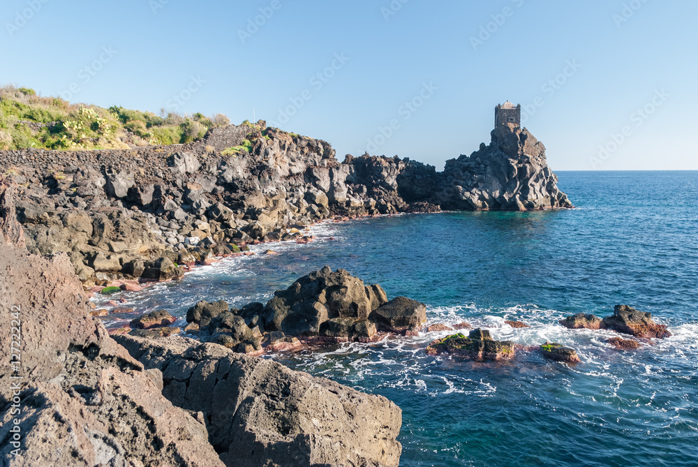Ταπετσαρία Rocky coastline of lava cliff near Acireale (Sicily), with a watchtower in the b