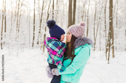 Young brunette mother with her daughter outdoors. Winter time