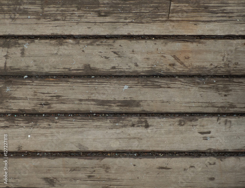 Ship deck surface. Old dirty boards with some stones and water between them. Wooden texture.