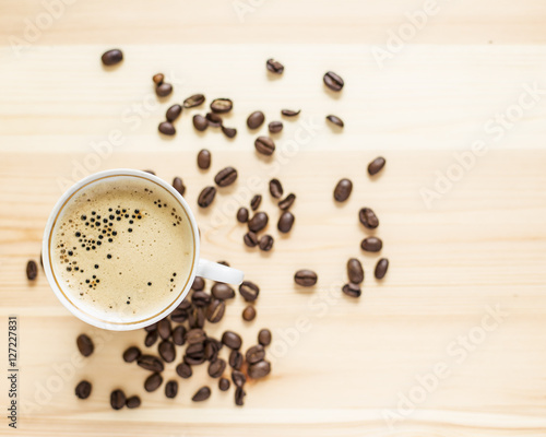 Appetizing cup of coffee and grain lying on the wooden table
