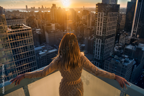 Rich woman enjoy the sunset standing on the balcony at luxury apartments in New York City. Luxury life concept. Succesful B.businesswoman relax.