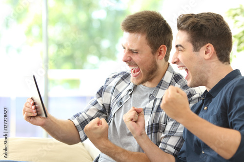 Canvas Print Excited friends watching tv on a tablet