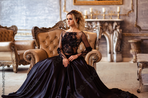 Фотография Beautiful young woman in gorgeous black evening dress with perfect makeup and ha