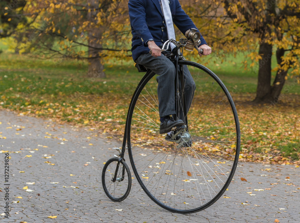 Penny-farthing bicycle in a park, unidentified man riding a vintage bike in  a park Stock Photo | Adobe Stock