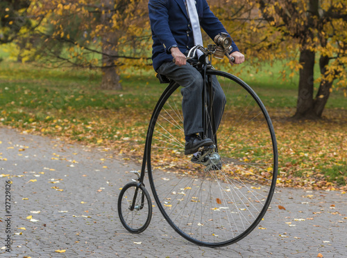 Penny-farthing bicycle in a park, unidentified man riding a vintage bike in a park