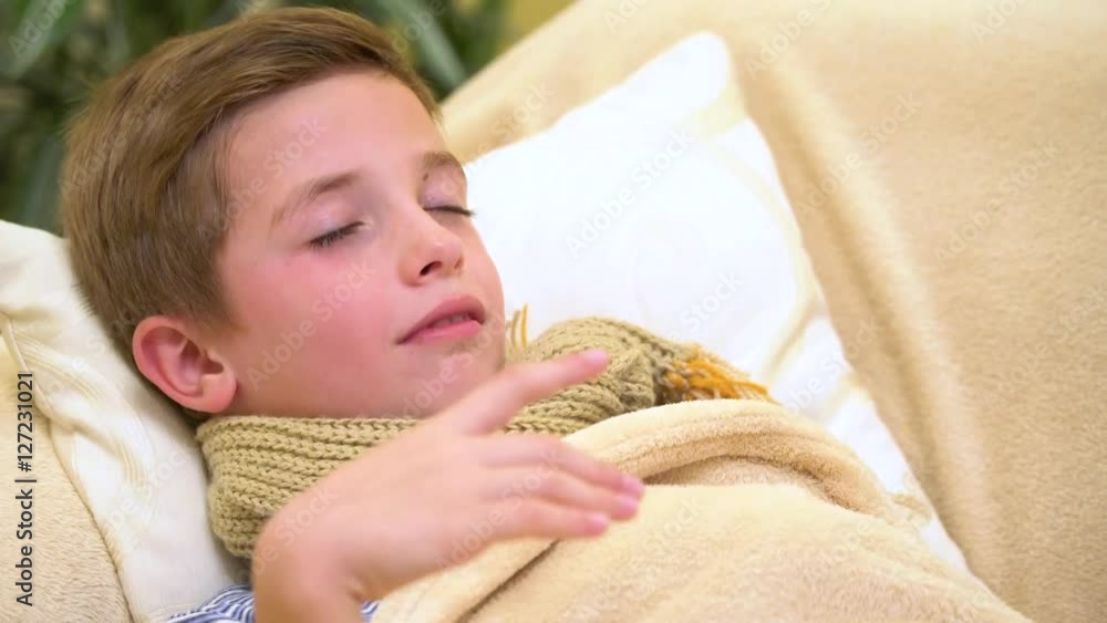 Sick child boy lying in bed with a fever,resting, coughing and blowing