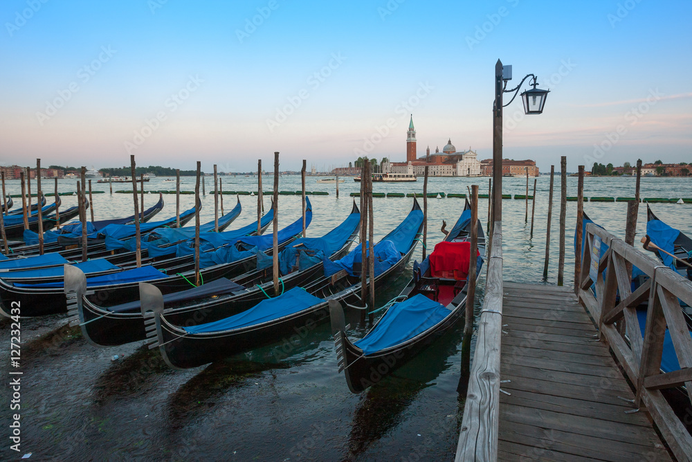 Gondolas moored by Saint Mark square with San Giorgio di Maggiore church in the background - Venice, Venezia, Italy.