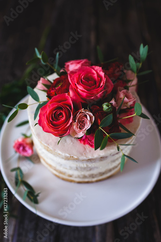Appetizing wedding cake with flowers in rustic style on dark background