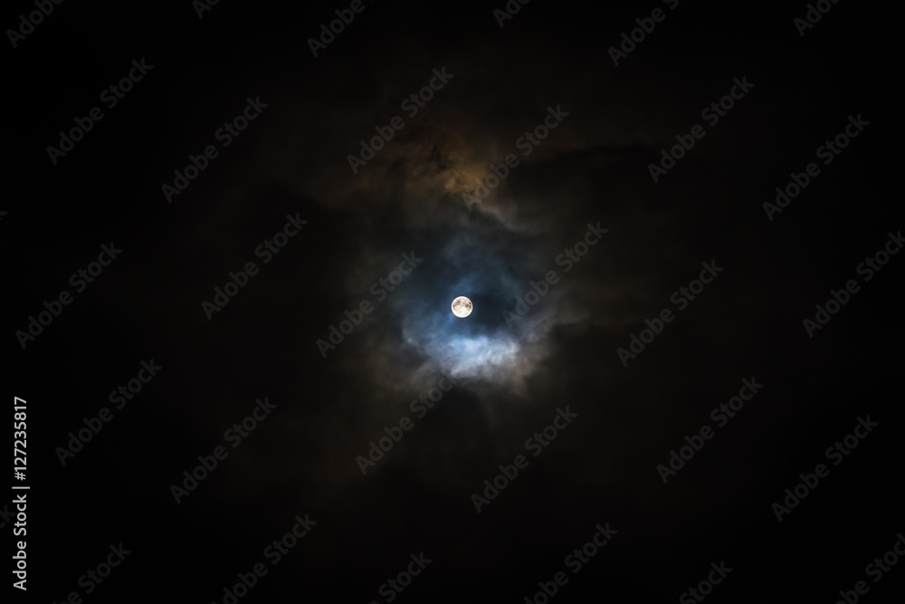 Super moon in magic cloudy night sky. Illuminated clouds colorized like a nebula or galaxy in space. Super moon in magic cloudy night sky. Illuminated clouds colorized like a nebula or galaxy in space.