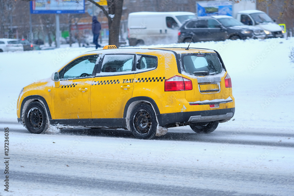 Moscow, Russia - November, 12, 2016: Taxi on a snow-covered road after high snow-storm in Moscow, Russia Moscow, Russia - November, 12, 2016: Taxi on a snow-covered road after high snow-storm in Moscow, Russia