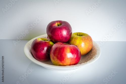 Apples in a plate on white shelf