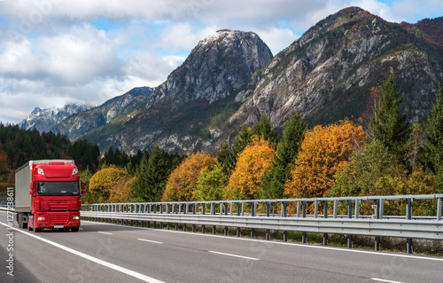 Red truck driving on the highway in the Alps.