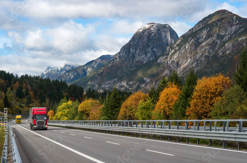 Red truck driving on the highway in the Alps.