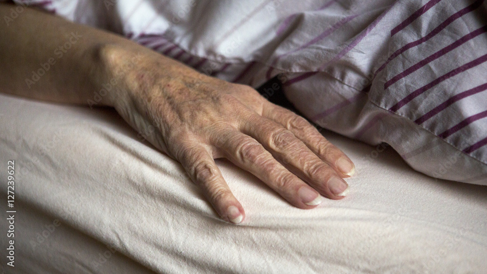 closeup of old female hand in bed closeup of old female hand in bed
