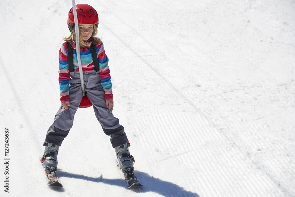 Naklejka premium Happy child girl enjoying vacation in winter resort. Little girl skiing in mountains. Active sportive toddler wearing helmet learning to ski. Winter sport for family. Skier racing in snow.
