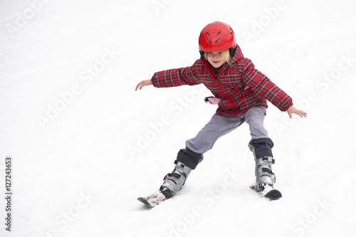 Happy child girl enjoying vacation in winter resort. Little girl skiing in mountains. Active sportive toddler wearing helmet learning to ski. Winter sport for family. Skier racing in snow. © Petr Bonek