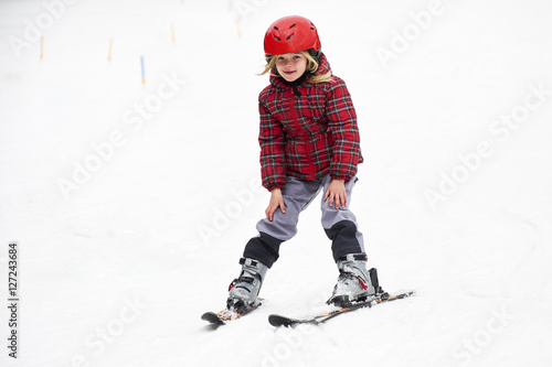 Happy child girl enjoying vacation in winter resort. Little girl skiing in mountains. Active sportive toddler wearing helmet learning to ski. Winter sport for family. Skier racing in snow.