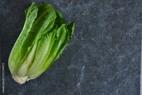 Romaine lettuce on black marble background. View from above.