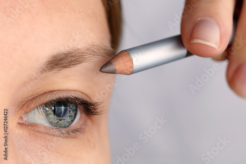 Young beautiful woman applying eyebrow pencil close up. Beauty, make up concept photo