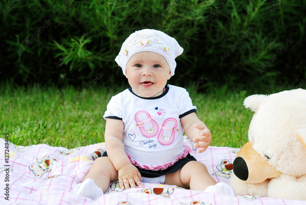 little girl sitting on the blanket and smiling at the camera little girl sitting on the blanket and smiling at the camera