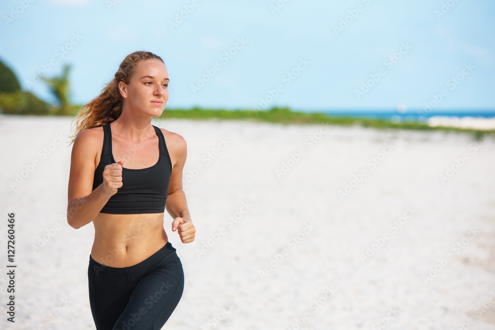 young fitness woman running at beach