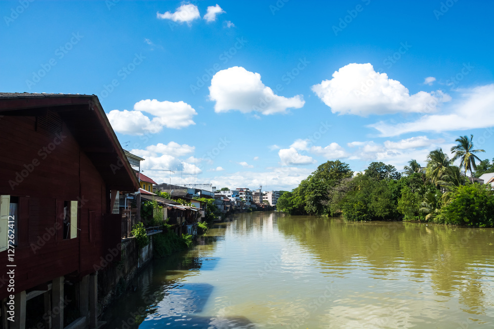 Fototapeta premium Urban canal village under blue sky and clouds, Thailand