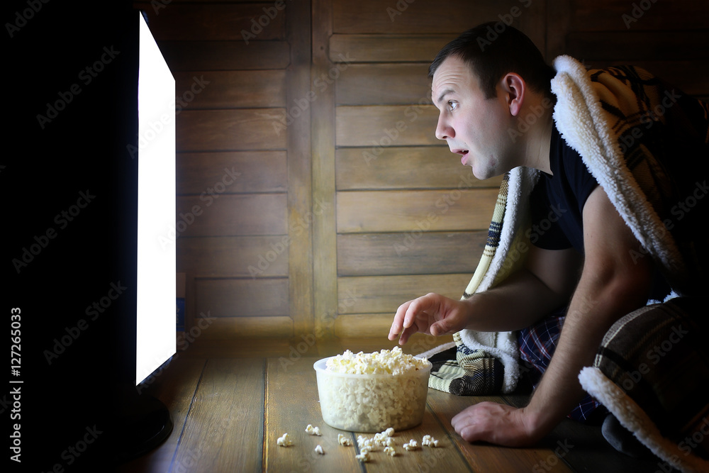 Fototapeta premium young man watching television at home on the floor