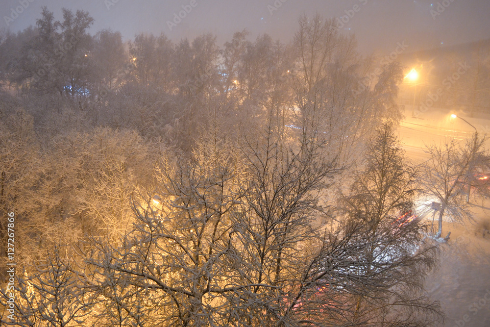 Winter. Evening. Snowstorm. Light lamps and cars