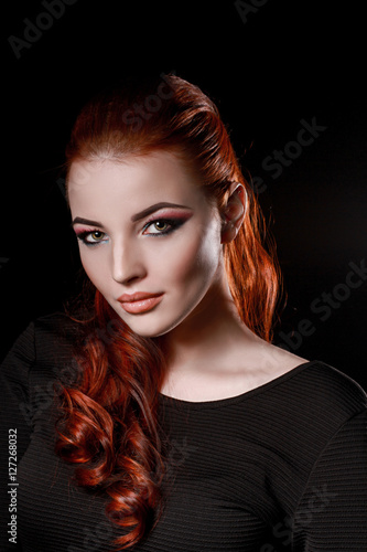 sexy redhead girl in black dress on a black background. beauty