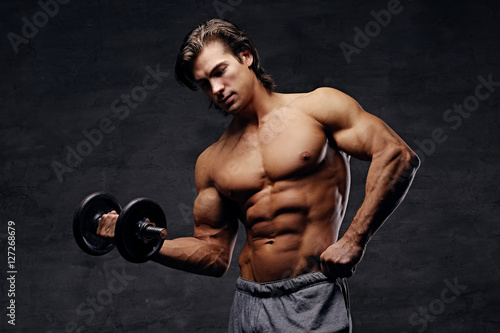 Shirtless abdominal male hold dumbbell.
